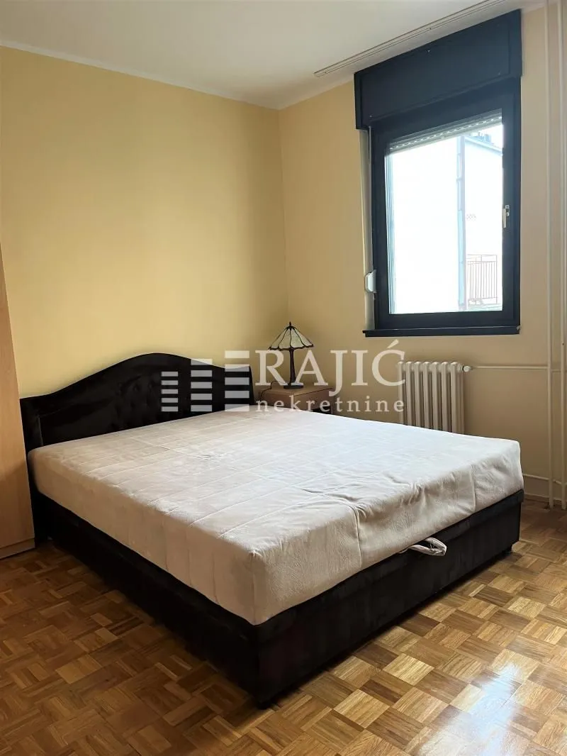 Bedroom with a double bed, parquet flooring, and a window.