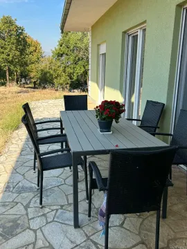 Terrace with a table, chairs, and flowers in front of the house. - image 8