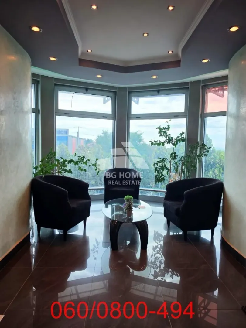 Smaller living room with armchairs and a glass coffee table in front of large windows.