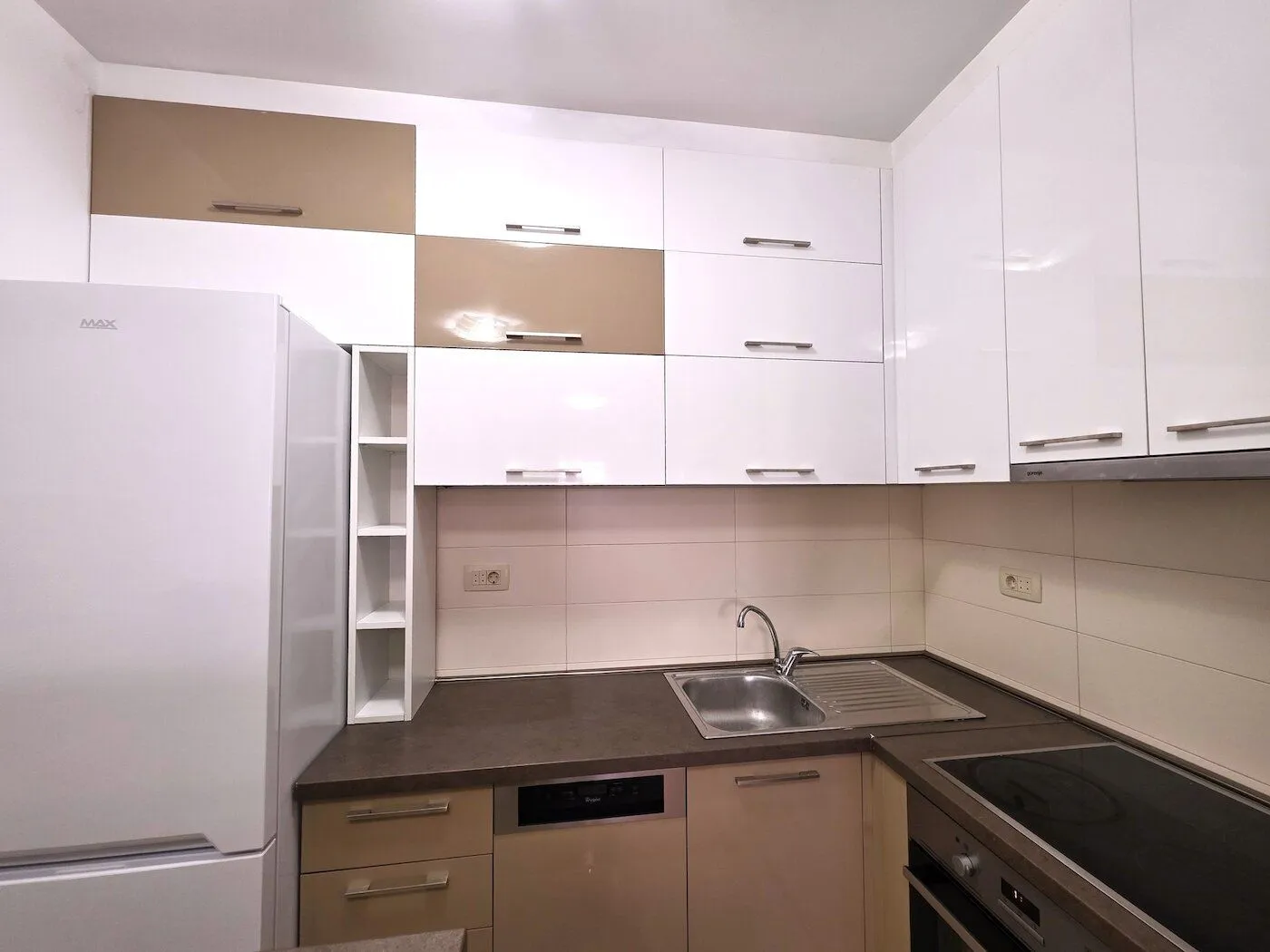 Kitchen equipped with white and beige cabinets and built-in appliances.