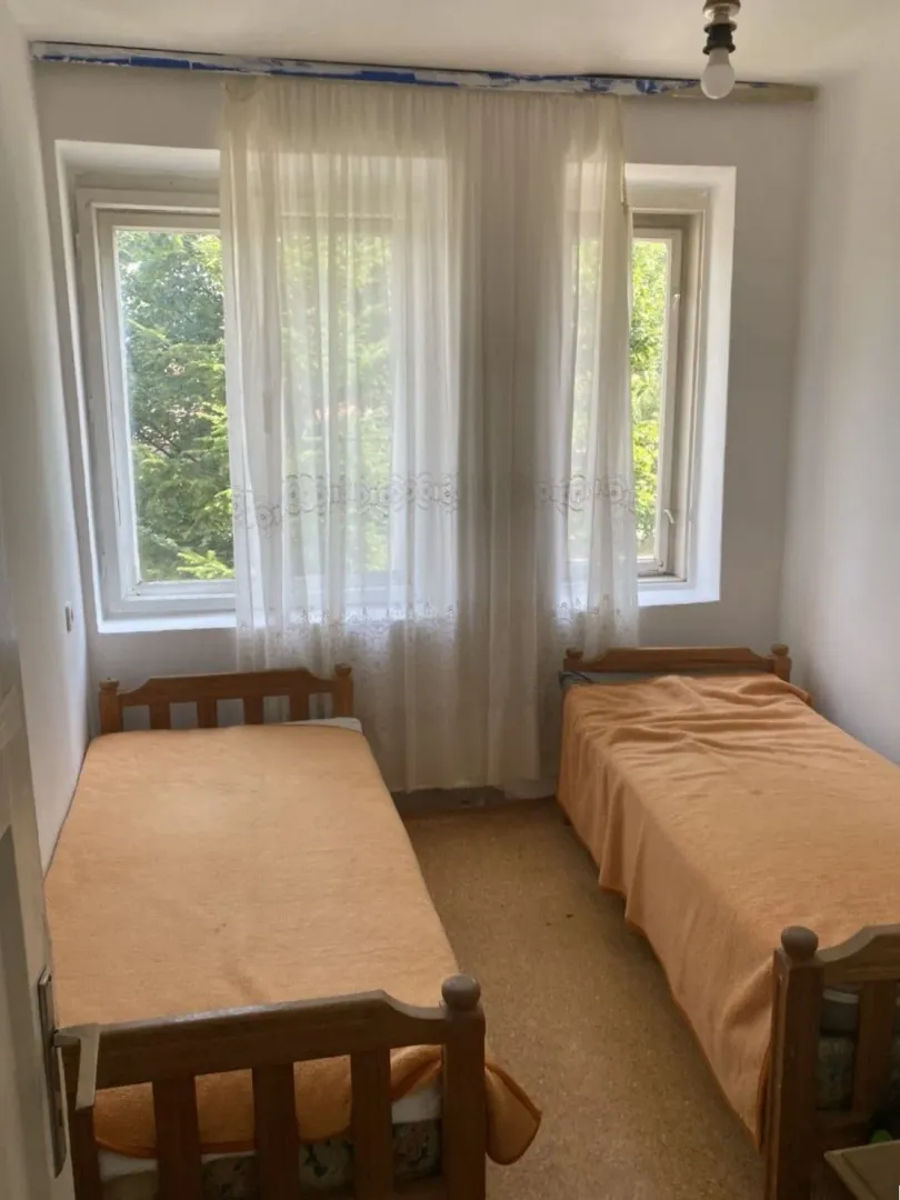 Small bedroom with two wooden beds and a window.