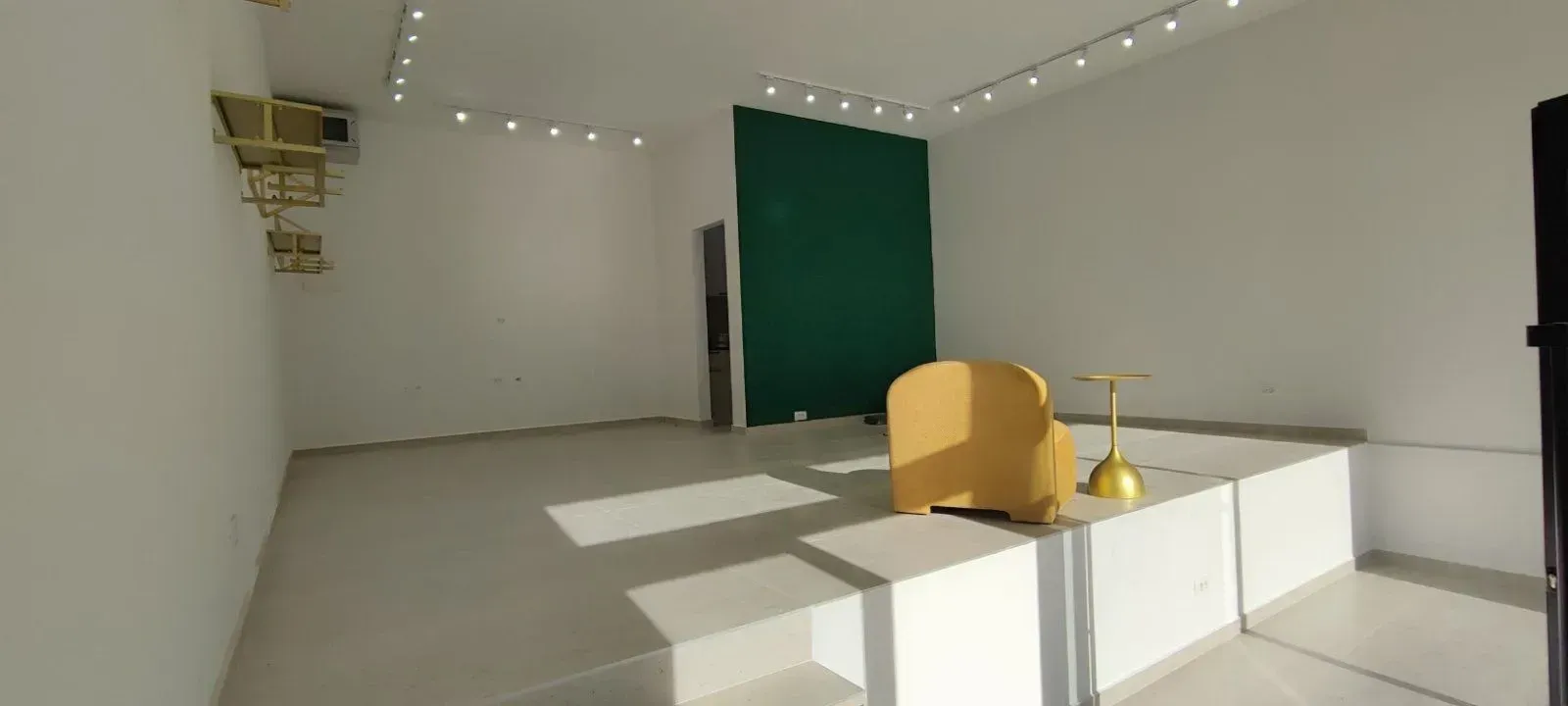Spacious bright room with a raised platform and a yellow armchair.