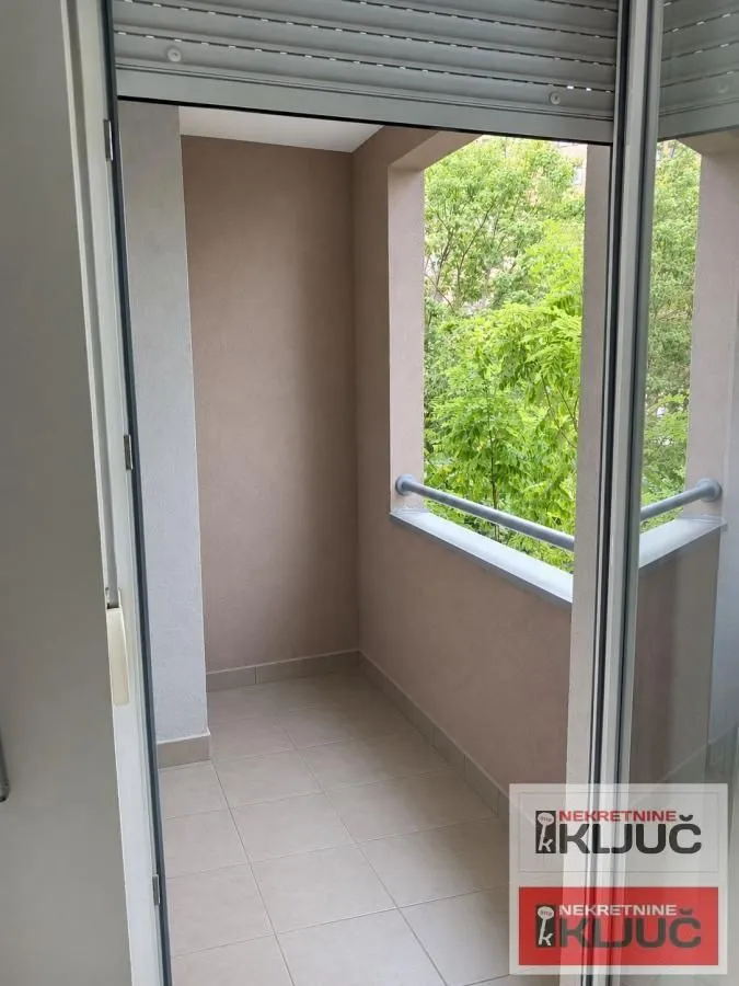 Manji popločani balkon sa pogledom na zelenilo.