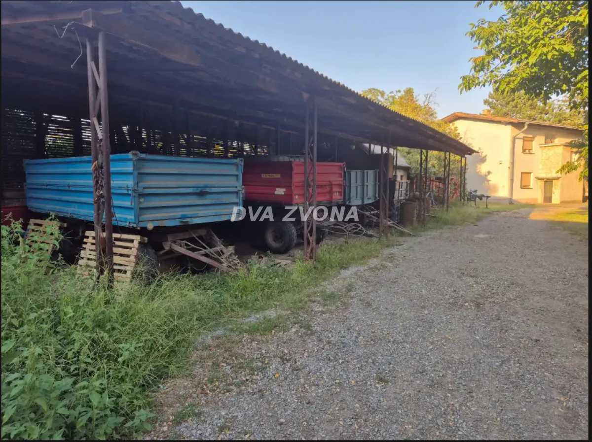 Natkriveni prostor sa poljoprivrednim prikolicama u dvorištu.