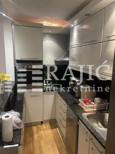 Small equipped kitchen with dark countertops and white cabinets.