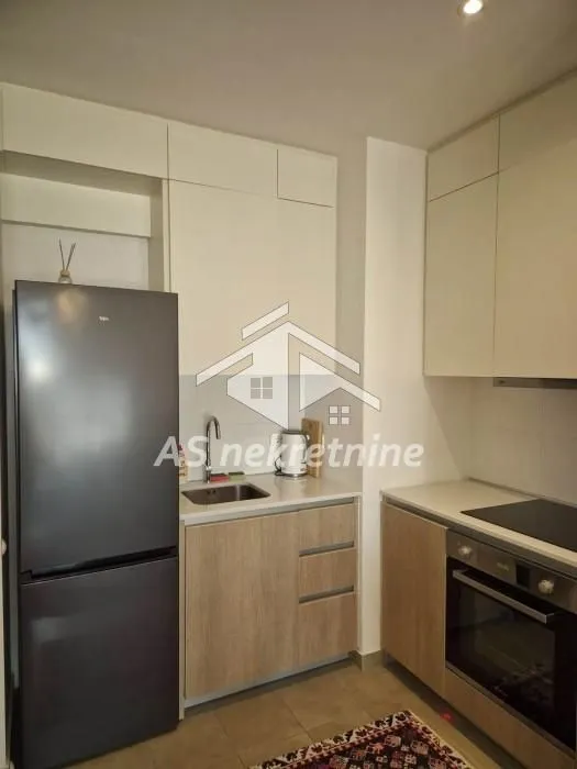 Compact modern kitchen with fitted appliances and a refrigerator.