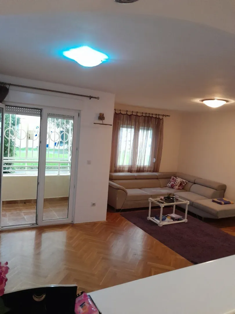 Svijetla dnevna soba sa ugaonom garniturom i izlazom na terasu.