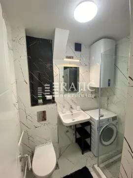 Small bathroom clad in marble tiles with a walk-in shower and washing machine. - image 9