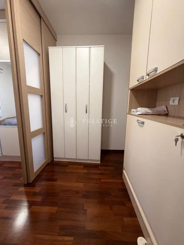 Manja spavaća soba sa ormarima i drvenim podom.