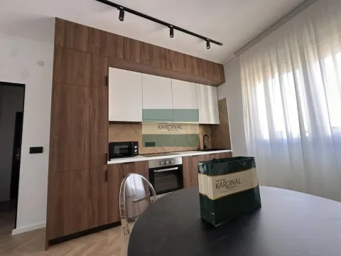 Moderna kuhinja sa drvenim elementima i trpezarijskim stolom u prvom planu. - image 2