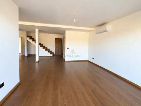 Prazna dnevna soba sa drvenim podom, klima uređajem i stepeništem u pozadini. - image 3