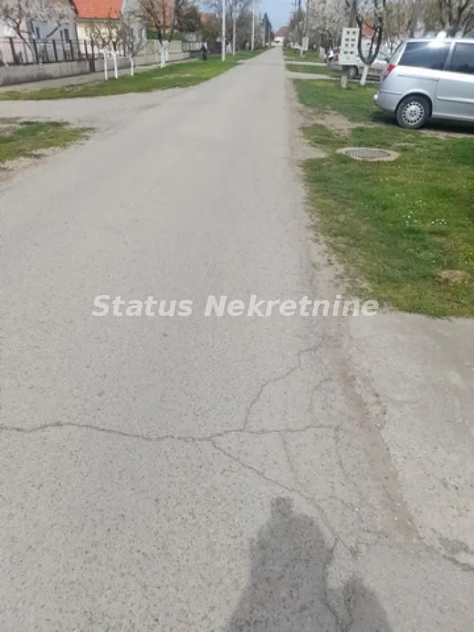 Asfaltirana ulica sa kućama i parkiranim automobilom u naselju.