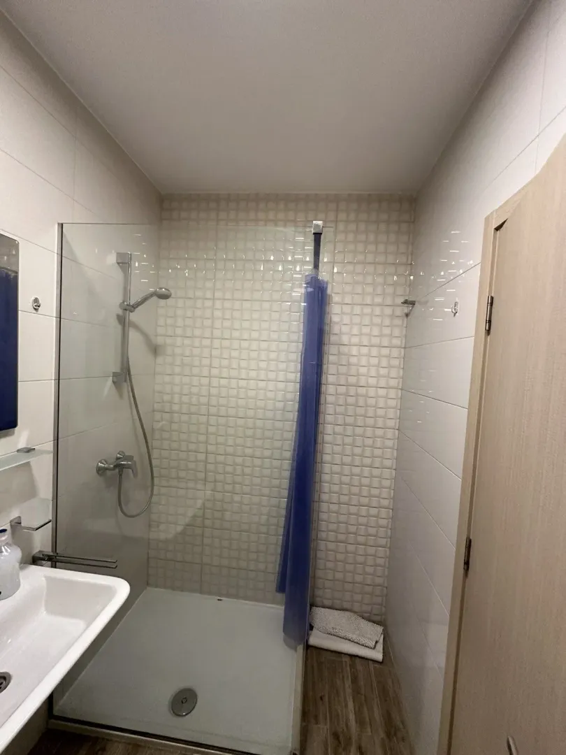 A simple bathroom featuring a shower cabin and white tiles.