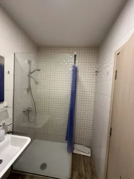 A simple bathroom featuring a shower cabin and white tiles. - image 9