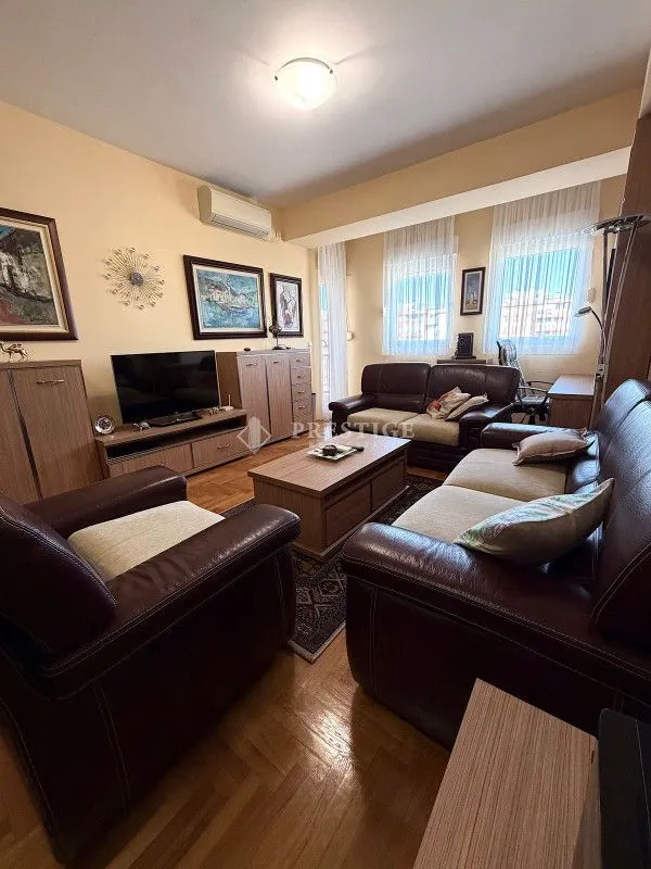 Living room with a sofa set, TV unit, and parquet flooring.
