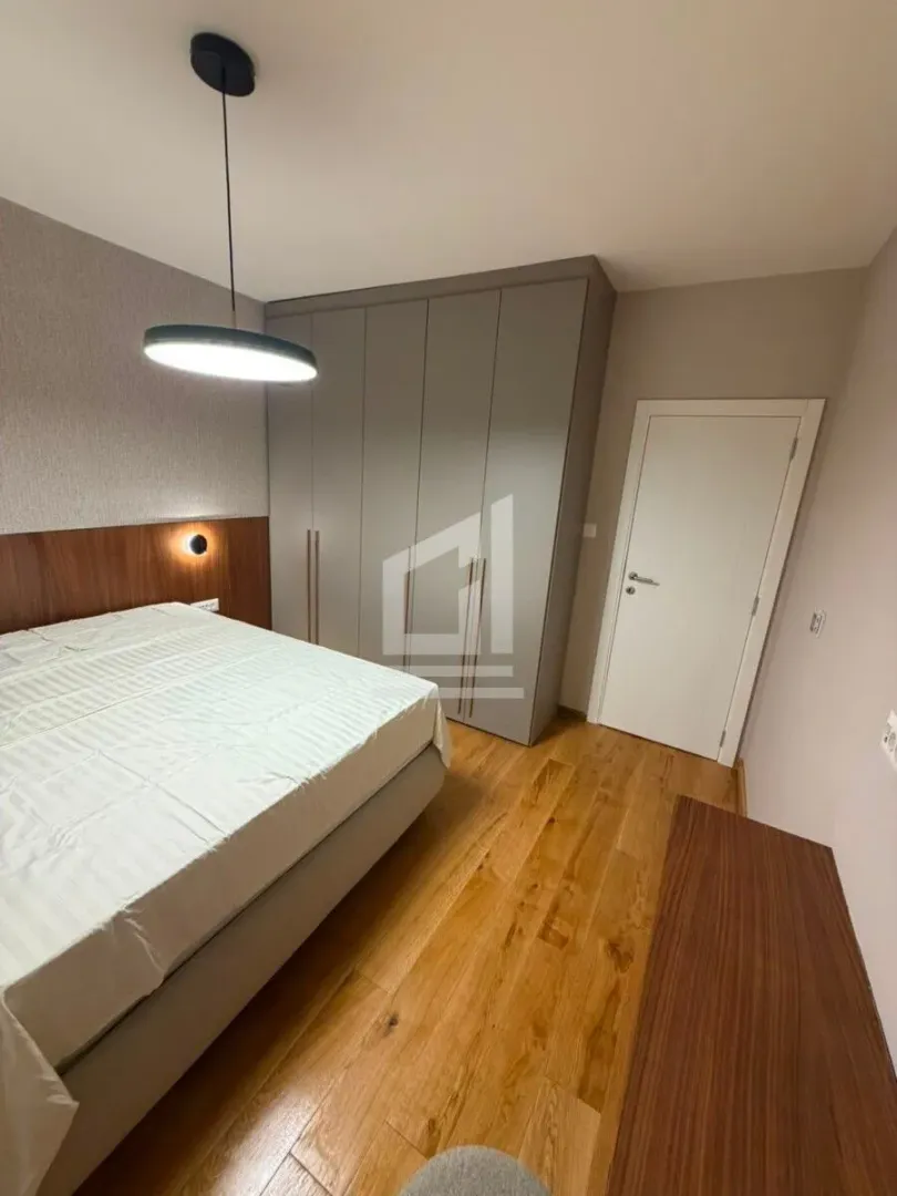 Furnished bedroom with a double bed, wardrobe, and wooden flooring.