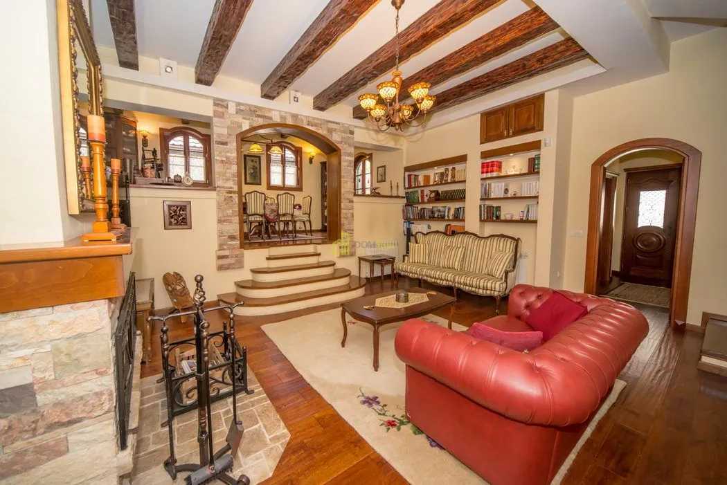 Spacious living room with a fireplace, exposed wooden ceiling beams, and classic furniture.