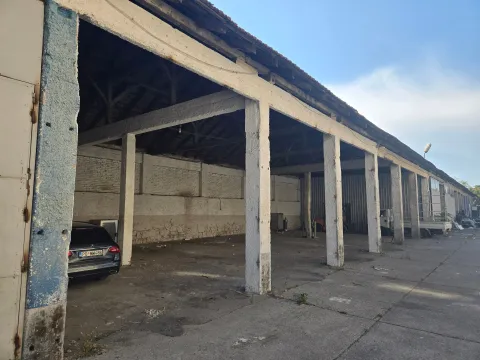 Exterior view of a large covered warehouse with concrete pillars. - image 3