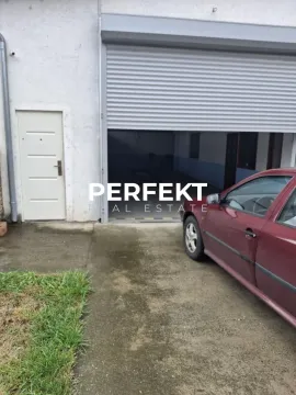 Exterior view of the garage entrance with a roller door and a parked car. - image 8