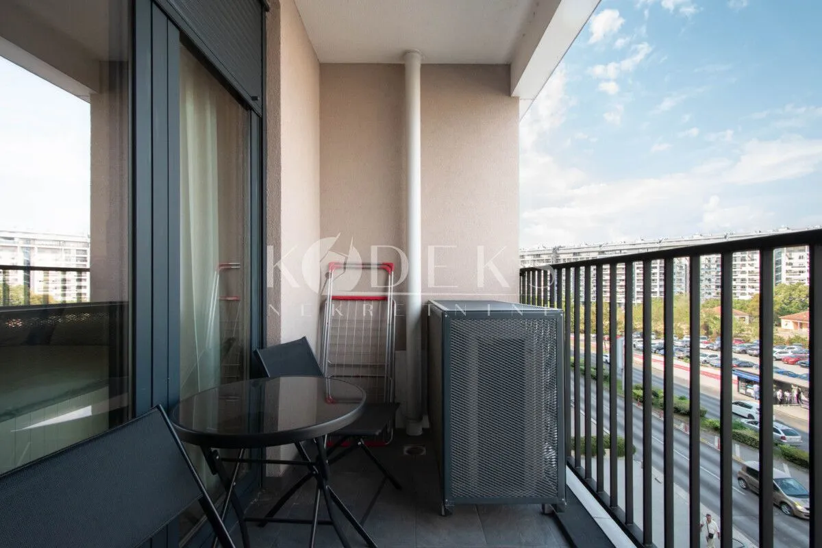 Manji namješten balkon sa stolom, stolicama i pogledom na ulicu.