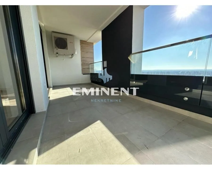 Spacious covered balcony with a glass railing and a view.