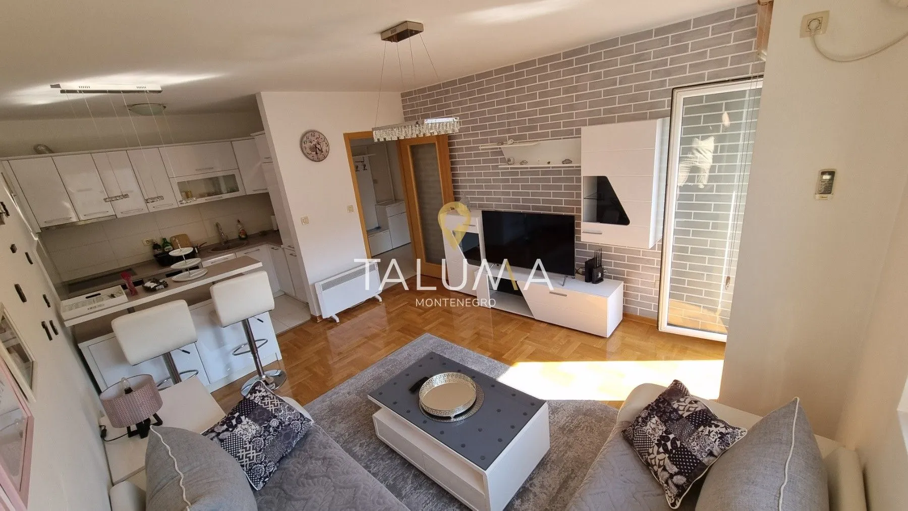 Living room connected to the kitchen, featuring a sofa set and a TV.
