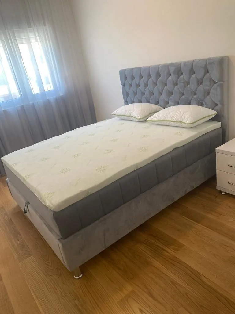 Svijetla spavaća soba sa velikim bračnim krevetom i noćnim ormarićem.