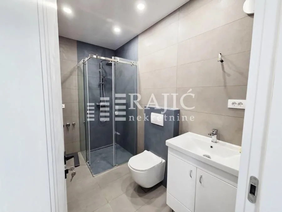 Modernly equipped bathroom with a shower cabin and a washbasin.