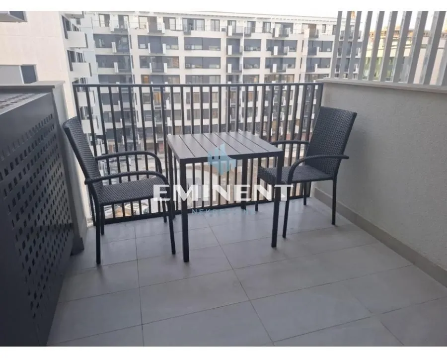 Namešten balkon sa stolom i dve stolice i pogledom na zgrade.