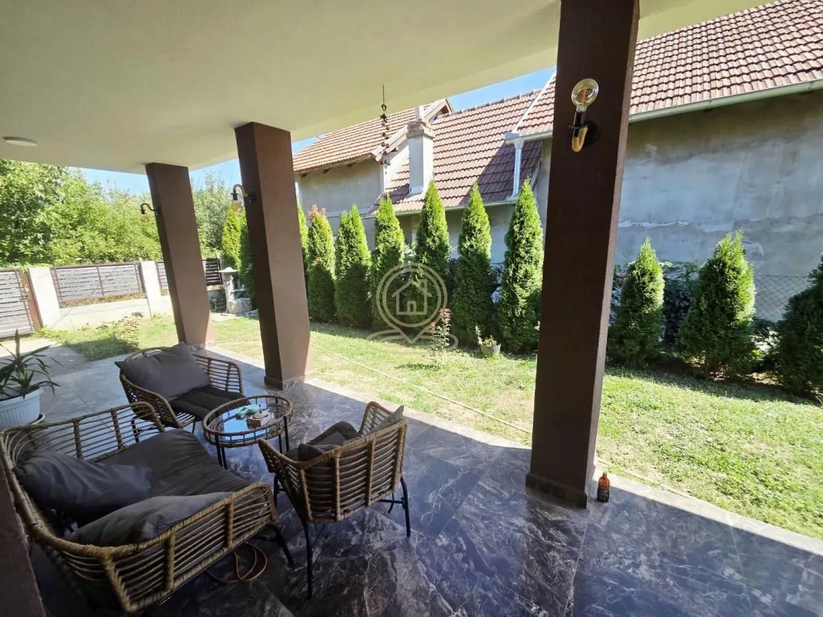 Natkrivena terasa sa garniturom za sedenje i pogledom na dvorište.
