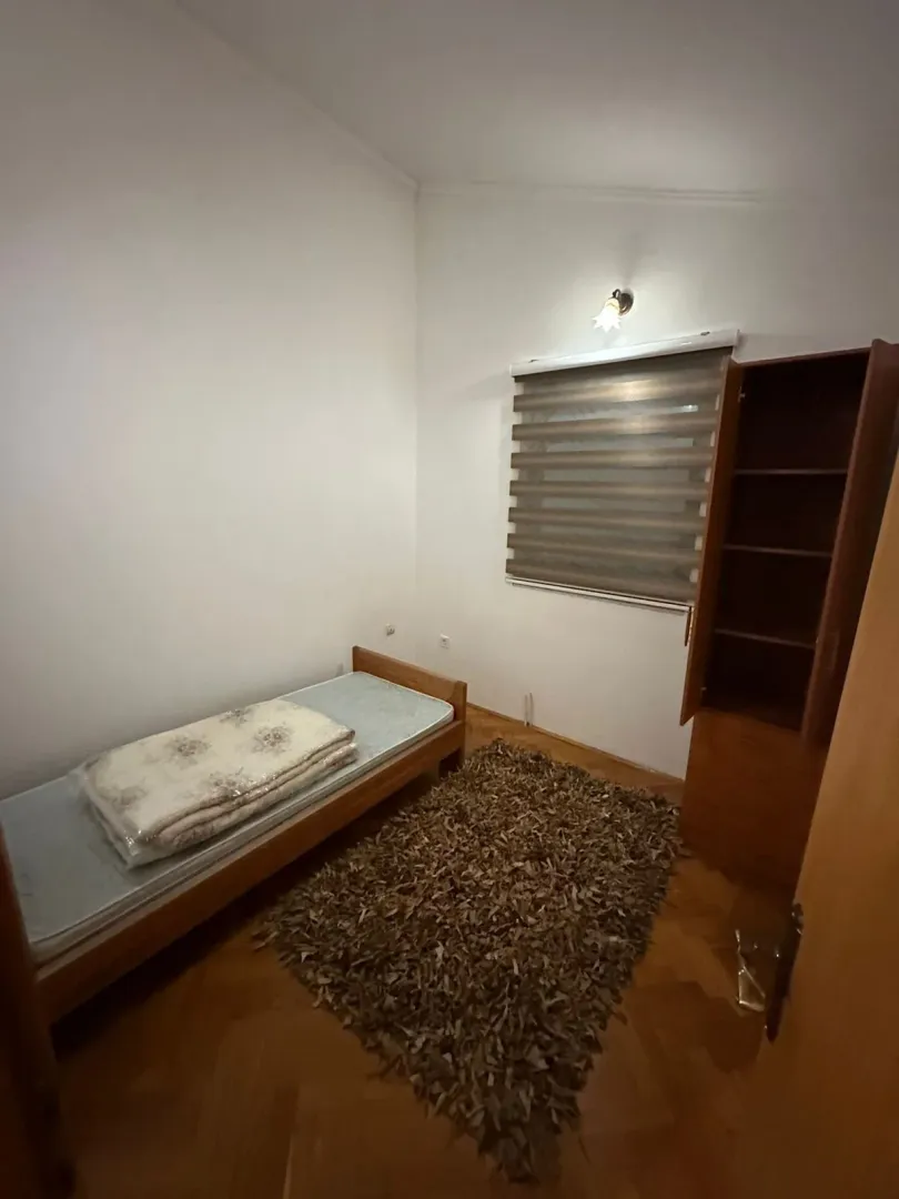 A simple bedroom featuring a single bed, a wardrobe, and a rug.