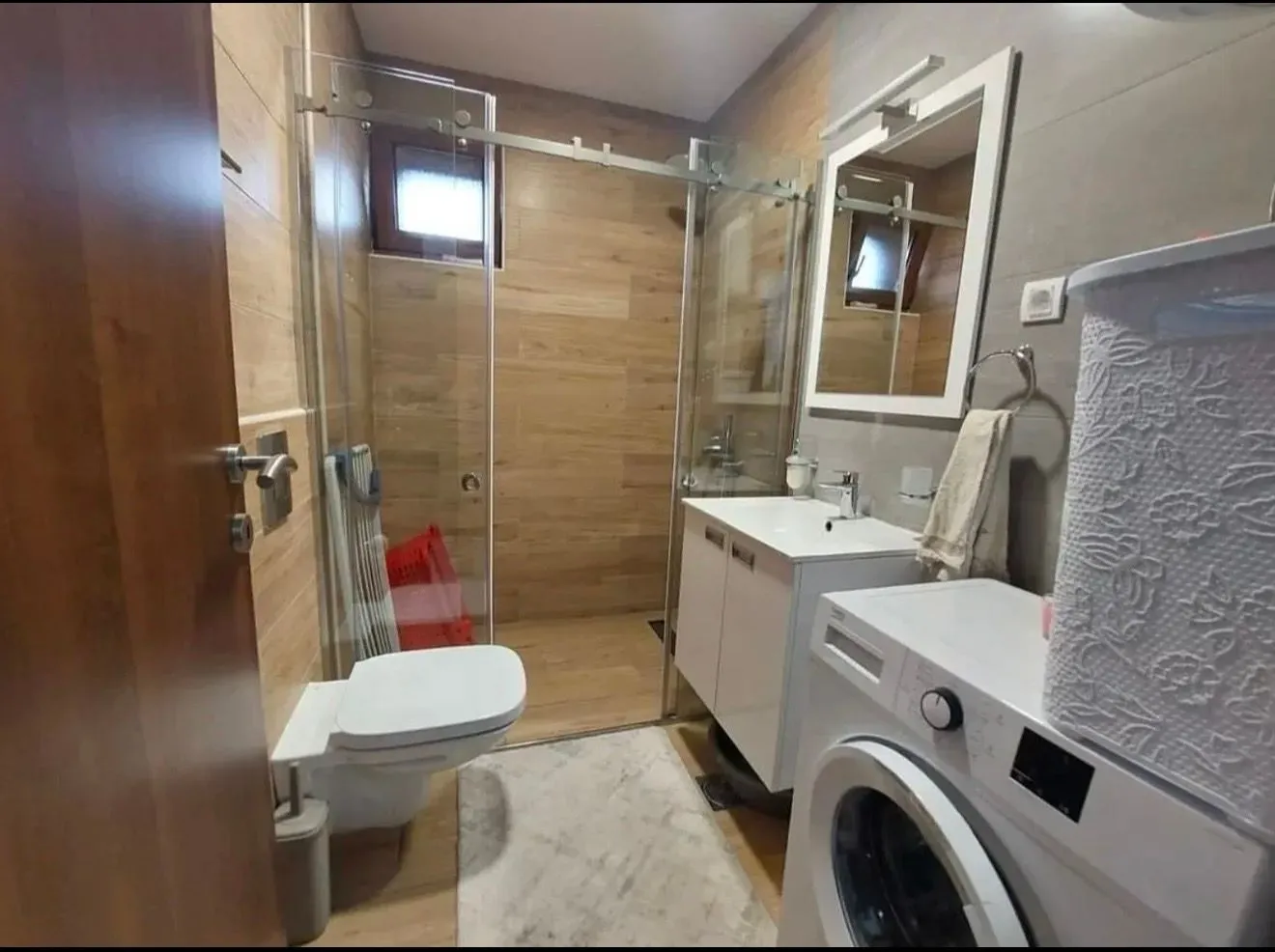 Moderno opremljeno kupatilo sa tuš kabinom, umivaonikom i veš mašinom.