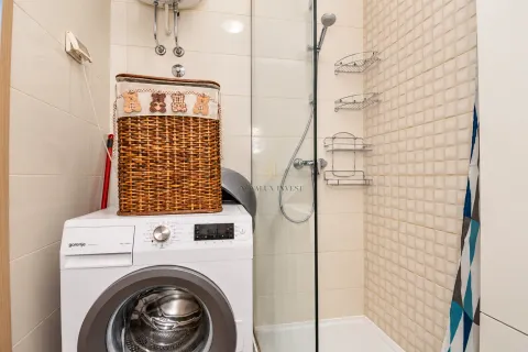 Bathroom with a shower cabin and a washing machine. - image 12
