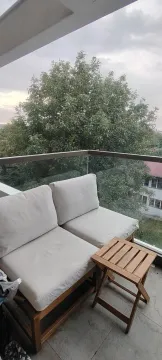 Small furnished balcony with seating furniture and a view of greenery. - image 7