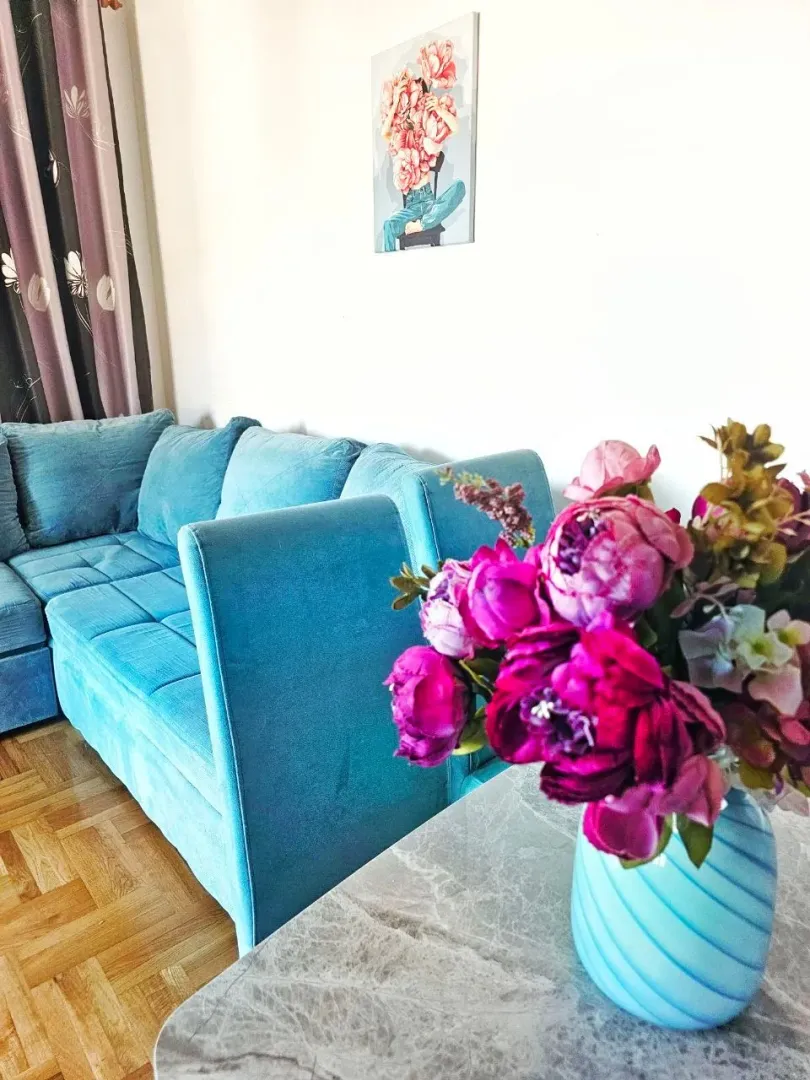 Living room with a blue sofa and a table with a vase of flowers.