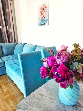 Living room with a blue sofa and a table with a vase of flowers. - image 10