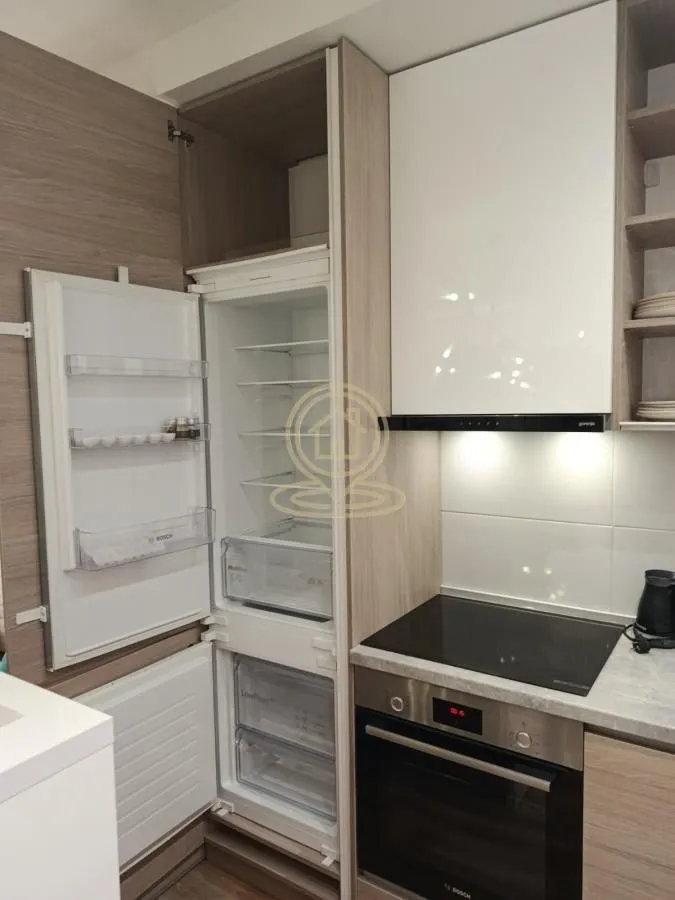 Compact kitchen with a built-in oven, hob, and refrigerator.