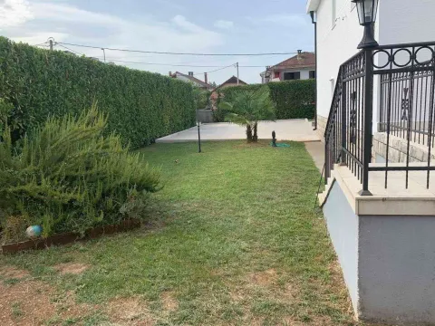 A landscaped yard with a green lawn, hedge, and house stairs. - image 10