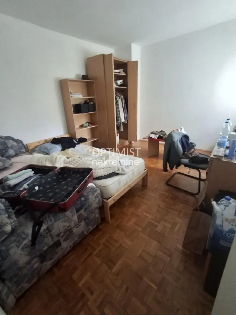 Nameštena spavaća soba sa krevetom, ormarom i drvenim podom.
