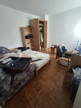 Nameštena spavaća soba sa krevetom, ormarom i drvenim podom. - image 4