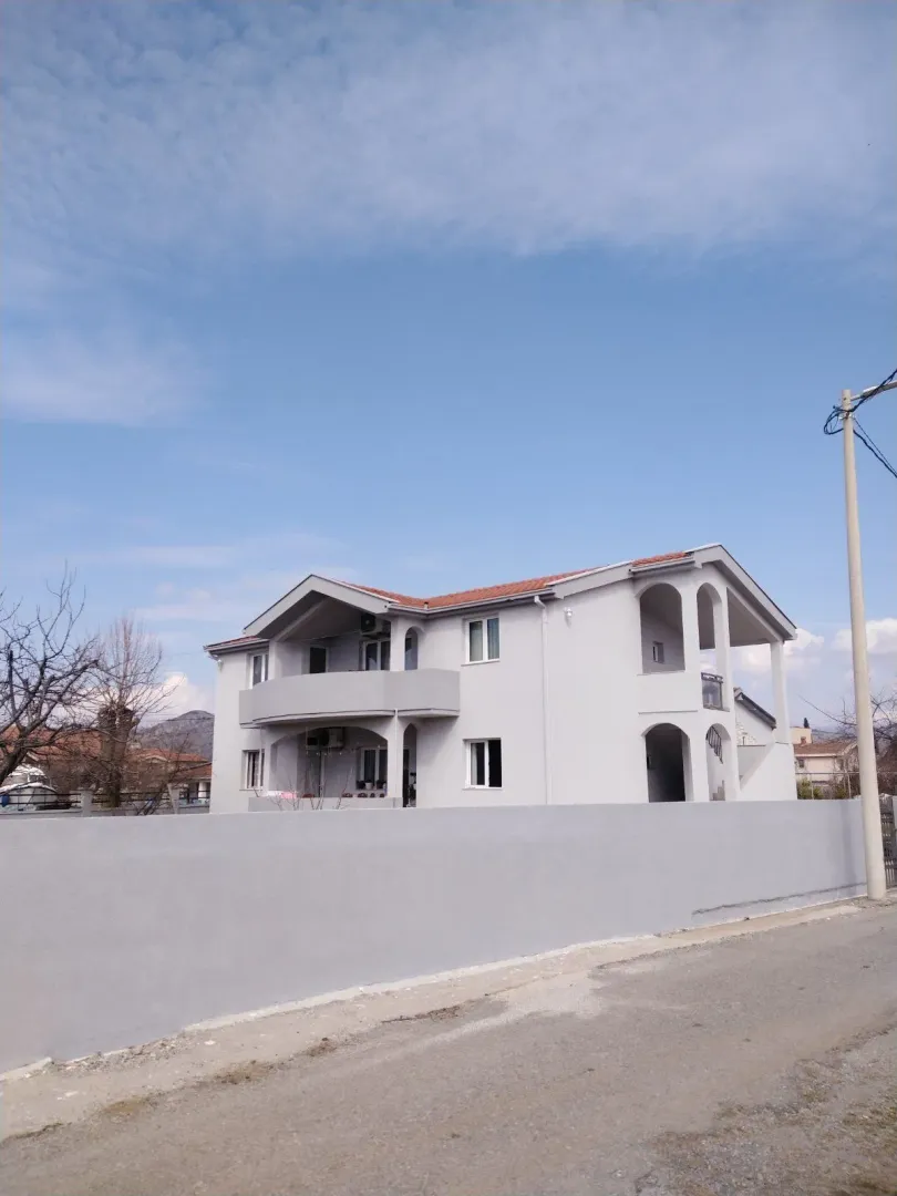 A two-story house with a gray facade and a fenced yard.