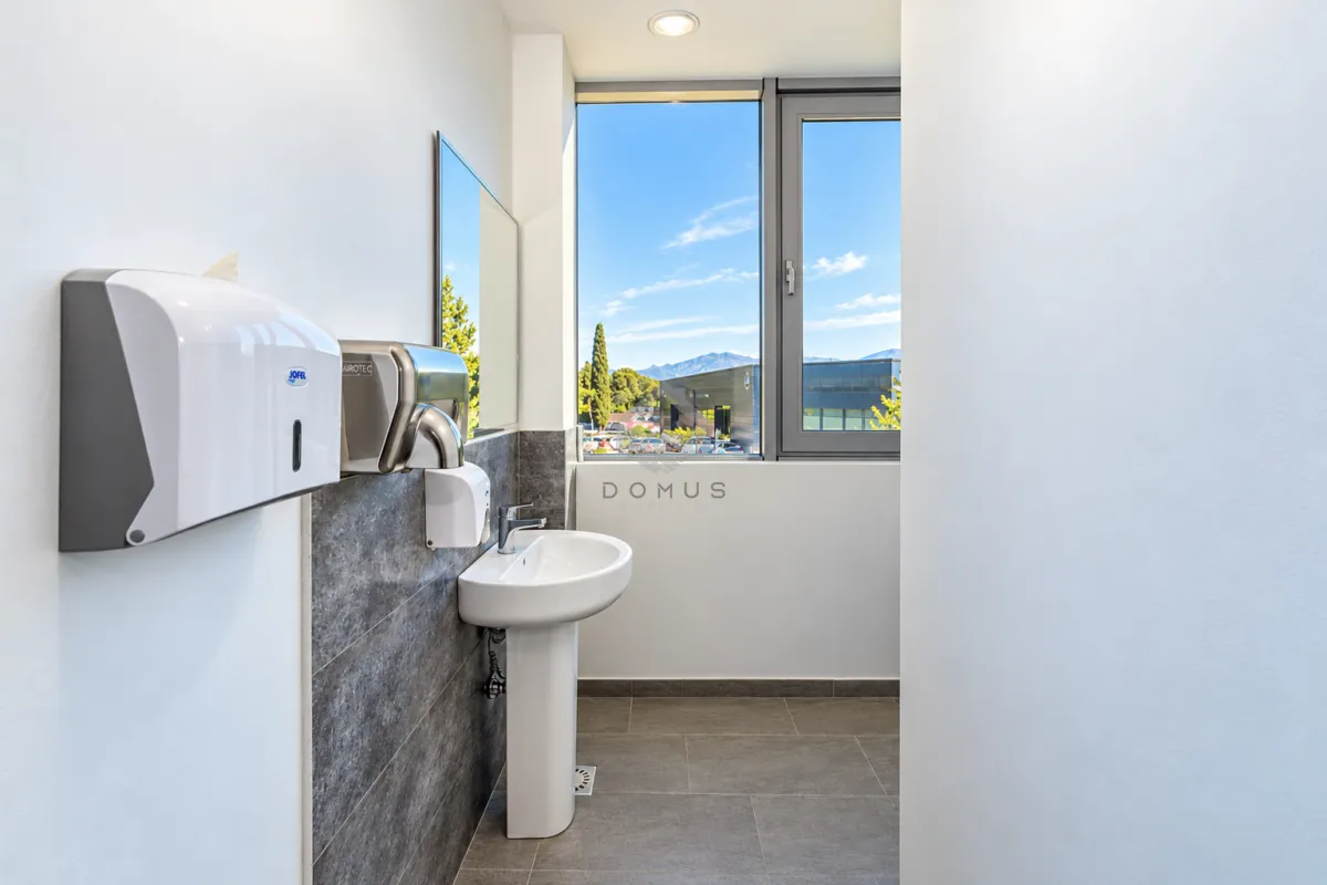 Modernly equipped bathroom with a washbasin, mirror, and soap and paper dispensers.