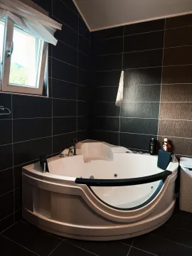 Kupatilo sa ugaonom hidromasažnom kadom i tamnim zidnim pločicama. - image 3