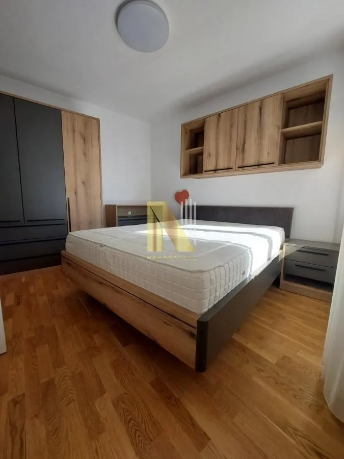 Nameštena spavaća soba sa bračnim krevetom, ormarom i zidnim elementima.