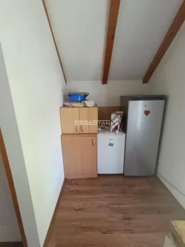 Small kitchen in the attic with wooden cabinets and a refrigerator. - image 9