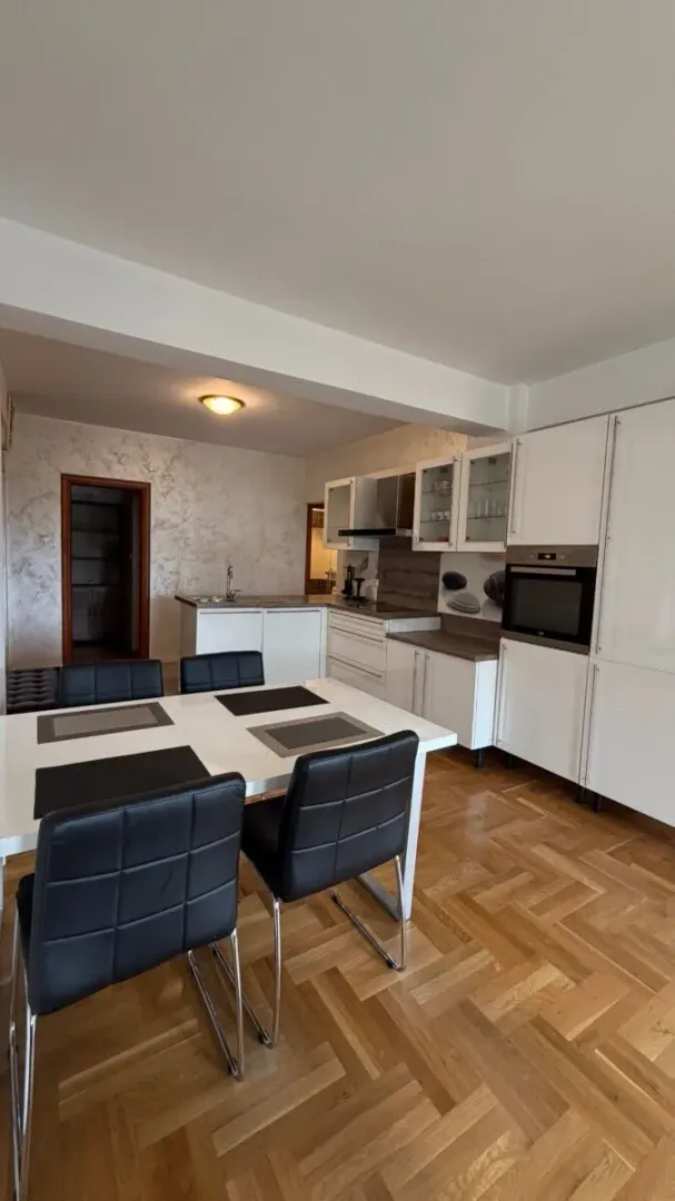 Dining area with a table and black chairs and a kitchen in the background.