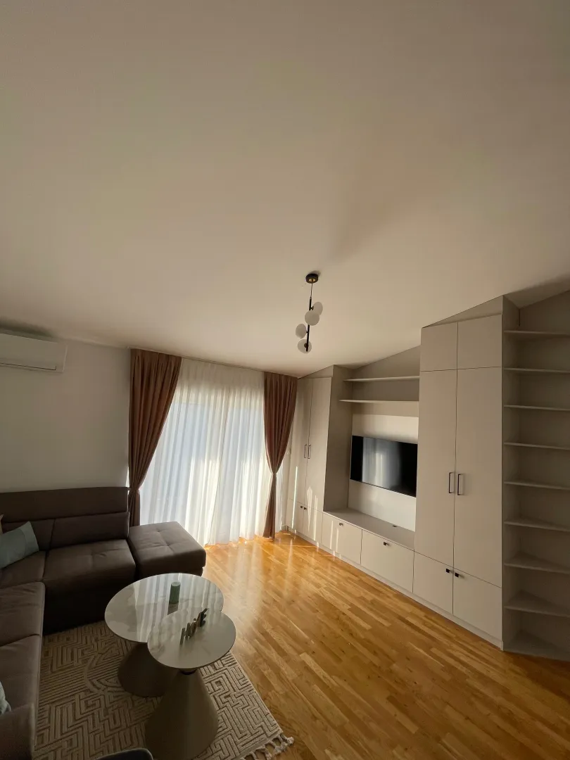 Living room with a sofa, TV unit, and hardwood flooring.