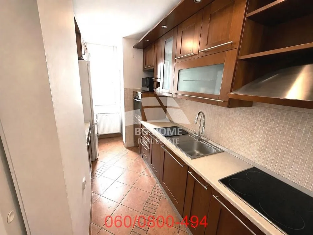 Narrow kitchen with wooden cabinets and tiled flooring.