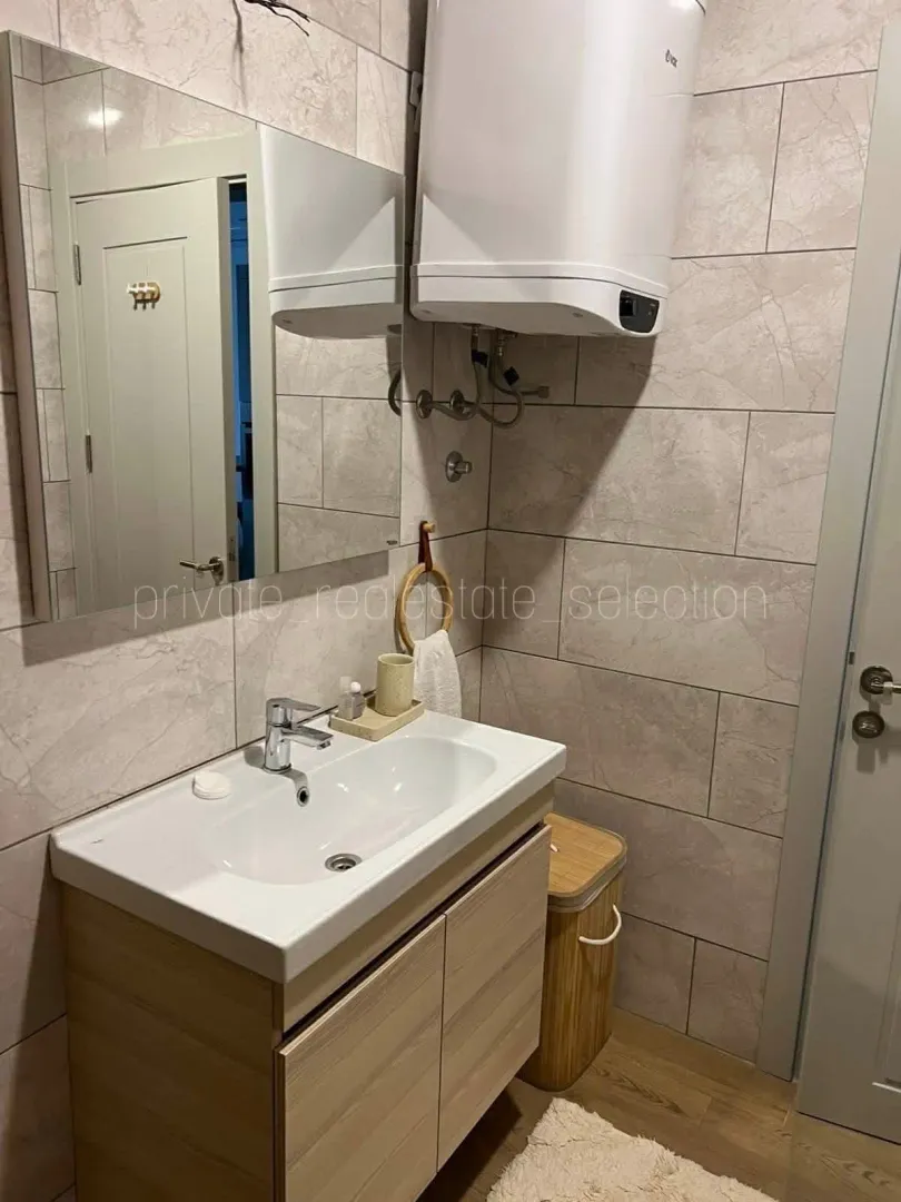 Smaller bathroom with a washbasin, mirror, and water heater.