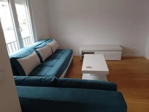 Simple living room with a blue sofa and white coffee table.